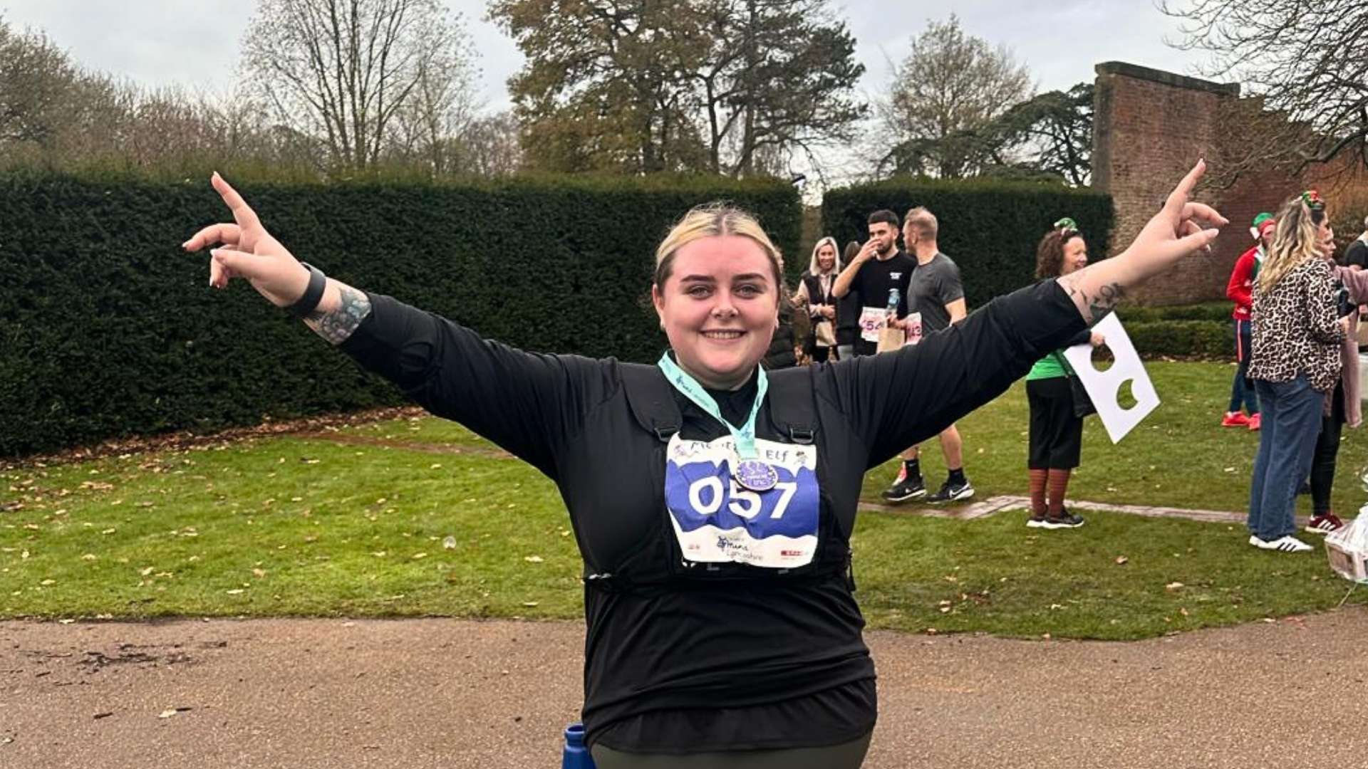 Chloe celebrating finishing the Mental Elf Lancashire fun run - standing proudly with her running vest