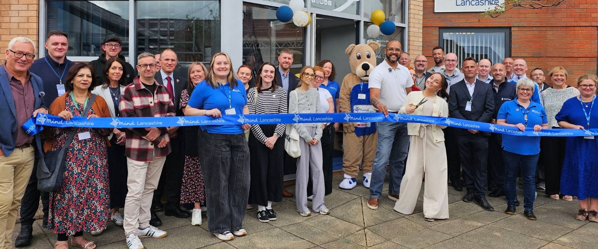 Lancashire Mind opens new office in Leyland, ribbon cutting with staff, guests and Clarke Carlise